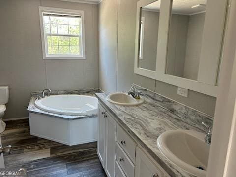 908 Bethel Freewill Rd, Baxley, GA 31513 - bathroom with toilet, double vanity, a garden tub, wood finished floors, and ornamental molding