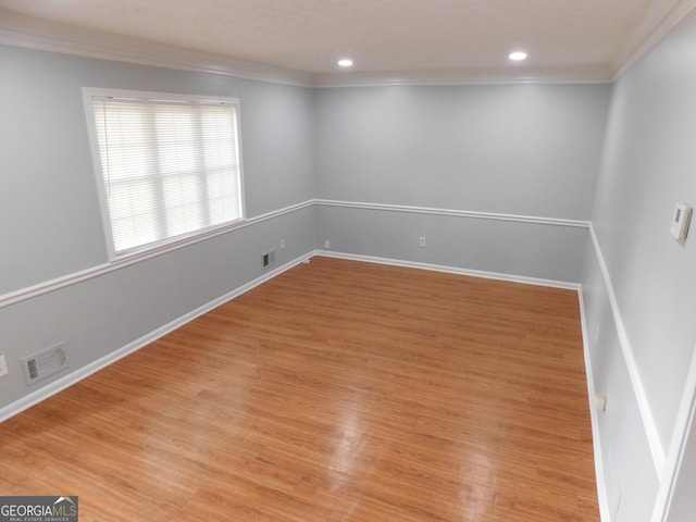 empty room with visible vents, ornamental molding, and light wood-type flooring