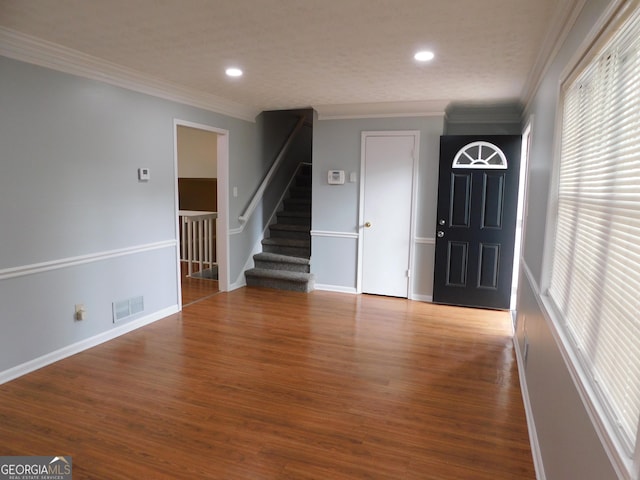 entryway with visible vents, wood finished floors, stairway, and crown molding