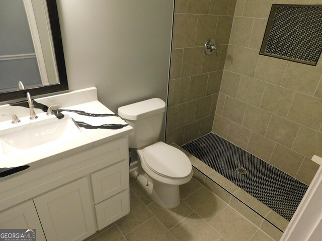 bathroom with tile patterned floors, tiled shower, toilet, and vanity