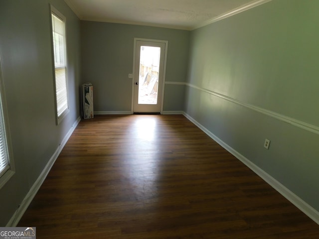 unfurnished room with crown molding, dark wood finished floors, and baseboards