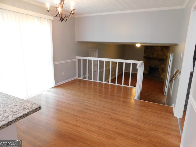 interior space featuring a chandelier, ornamental molding, a stone fireplace, and light wood-style flooring