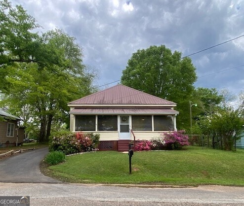 bungalow-style house with metal roof, entry steps, and a front yard