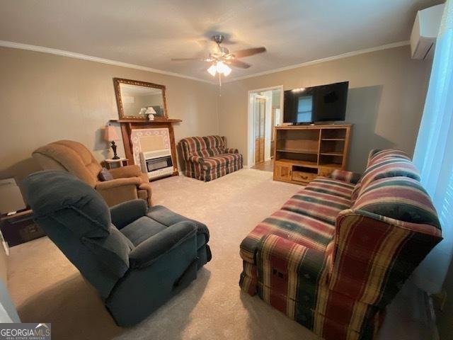 living area with crown molding, ceiling fan, carpet, and a fireplace