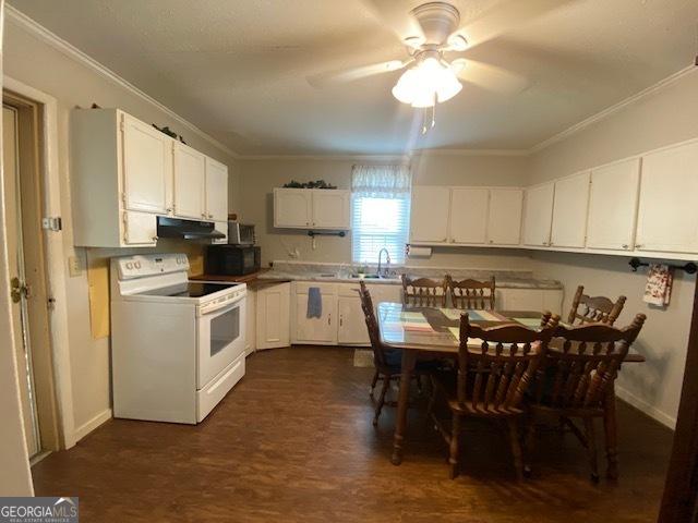 kitchen featuring under cabinet range hood, crown molding, white electric range oven, black microwave, and dark wood-style floors