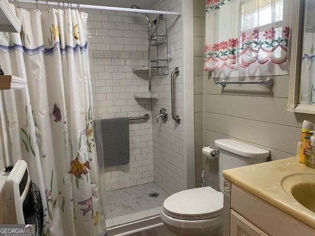 bathroom with a shower stall, vanity, toilet, and heating unit