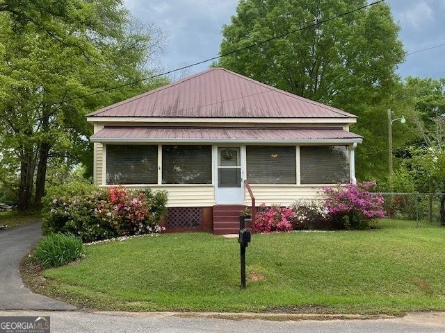 view of front of property featuring metal roof, entry steps, and a front yard