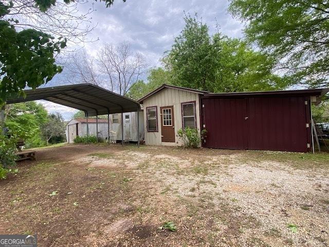 view of outbuilding with an outdoor structure, dirt driveway, and a carport