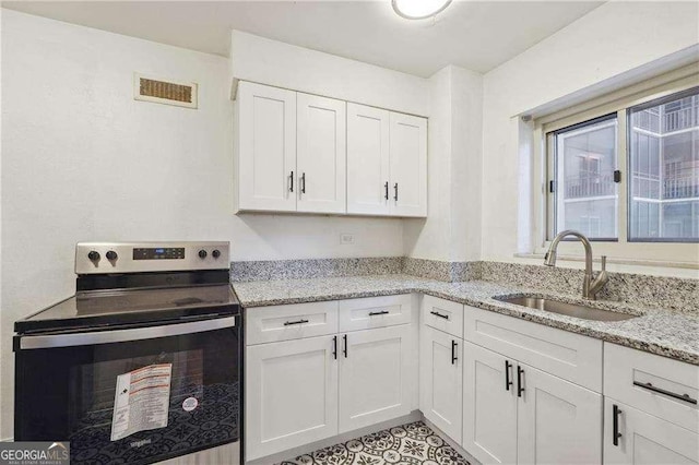 300 Peachtree St NE Unit 5A, Atlanta, GA 30308 - kitchen with a sink, electric range, white cabinetry, light stone countertops, and visible vents