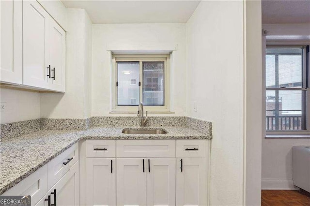 300 Peachtree St NE Unit 5A, Atlanta, GA 30308 - kitchen with radiator heating unit, a sink, baseboards, white cabinetry, and light stone countertops