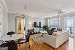 300 Peachtree St NE Unit 5A, Atlanta, GA 30308 - living room featuring arched walkways, crown molding, and a ceiling fan