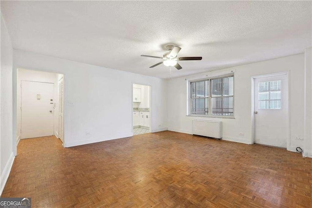 300 Peachtree St NE Unit 5A, Atlanta, GA 30308 - unfurnished living room featuring baseboards, a textured ceiling, ceiling fan, and radiator