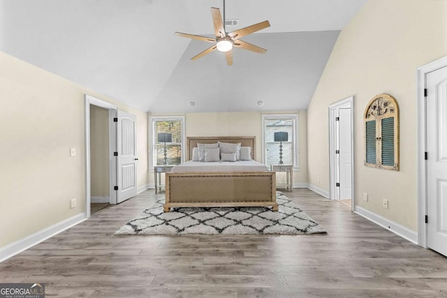 bedroom featuring visible vents, baseboards, wood finished floors, and high vaulted ceiling