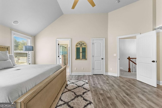 bedroom with high vaulted ceiling, ensuite bathroom, ceiling fan, light wood-style flooring, and baseboards
