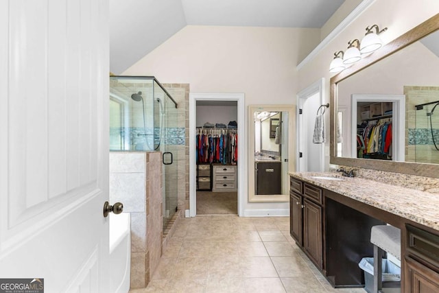 bathroom with tile patterned floors, a stall shower, a spacious closet, lofted ceiling, and vanity
