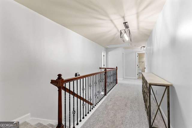 hall featuring baseboards, an upstairs landing, and carpet