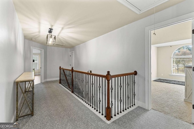 corridor with attic access, baseboards, carpet, an upstairs landing, and ornamental molding