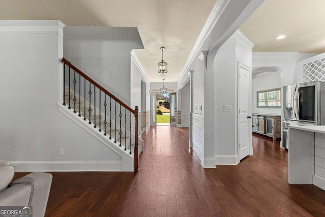 entryway featuring baseboards, arched walkways, dark wood-type flooring, and crown molding