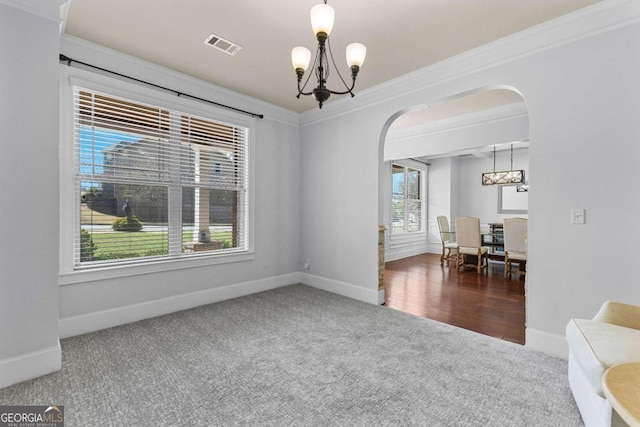 unfurnished room with visible vents, arched walkways, crown molding, carpet flooring, and a notable chandelier