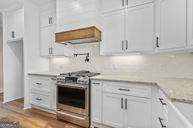 88 Northshore Ave, Jesup, GA 31545 - kitchen with light wood finished floors, stainless steel gas range, backsplash, white cabinetry, and custom range hood