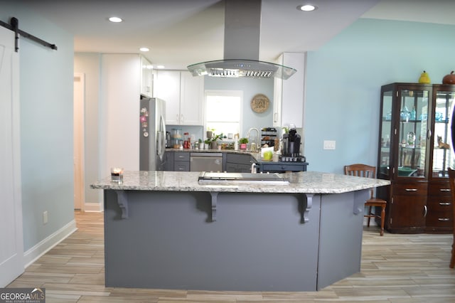 3440 Camelot Way, Loganville, GA 30052 - kitchen featuring island exhaust hood, a kitchen bar, light stone countertops, and stainless steel appliances