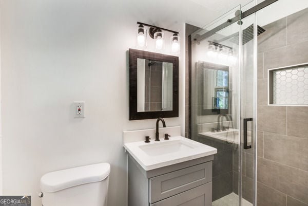 full bathroom featuring a shower stall, toilet, and vanity