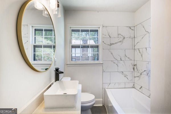 bathroom with a sink, toilet, tile patterned floors, and a wealth of natural light