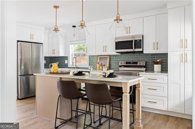 2086 Harold Ave SE, Smyrna, GA 30080 - kitchen featuring appliances with stainless steel finishes, a center island with sink, light countertops, white cabinetry, and tasteful backsplash