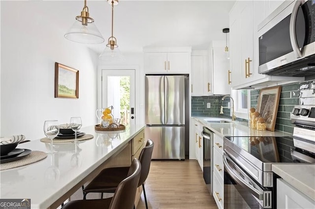 2086 Harold Ave SE, Smyrna, GA 30080 - kitchen featuring appliances with stainless steel finishes, a sink, backsplash, decorative light fixtures, and light countertops