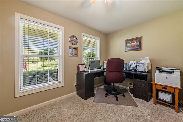office featuring a ceiling fan, baseboards, and light carpet