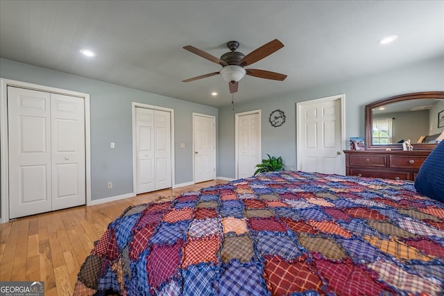 bedroom with two closets, ceiling fan, wood finished floors, and recessed lighting