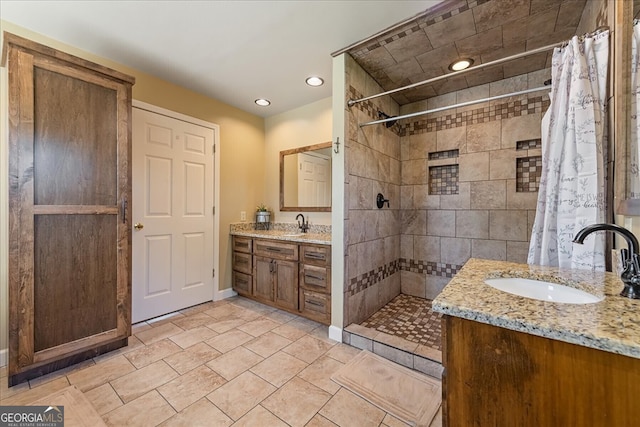 bathroom with recessed lighting, a tile shower, baseboards, and vanity