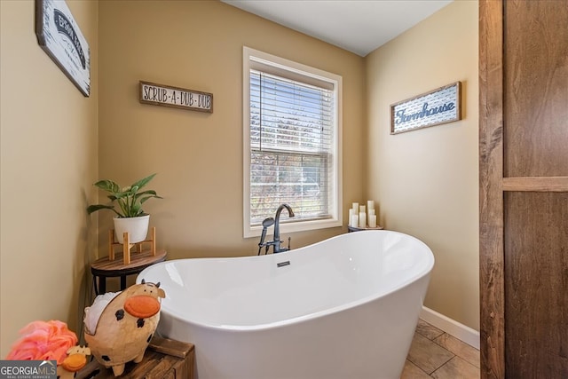 bathroom featuring a soaking tub, tile patterned floors, and baseboards
