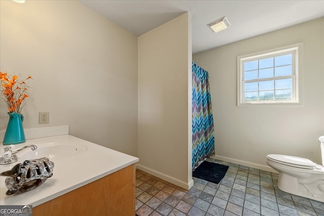bathroom featuring stone finish flooring, toilet, visible vents, and baseboards