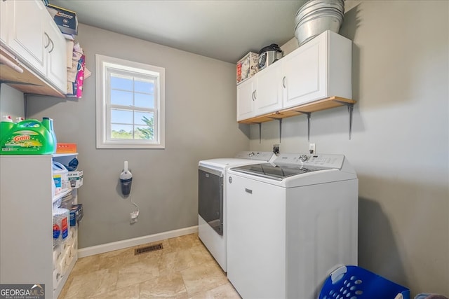 clothes washing area featuring separate washer and dryer, baseboards, visible vents, and cabinet space