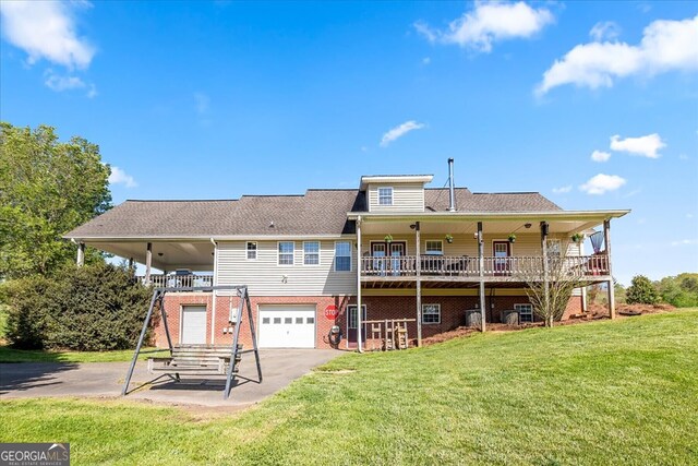 rear view of property featuring a garage, a yard, driveway, brick siding, and a deck