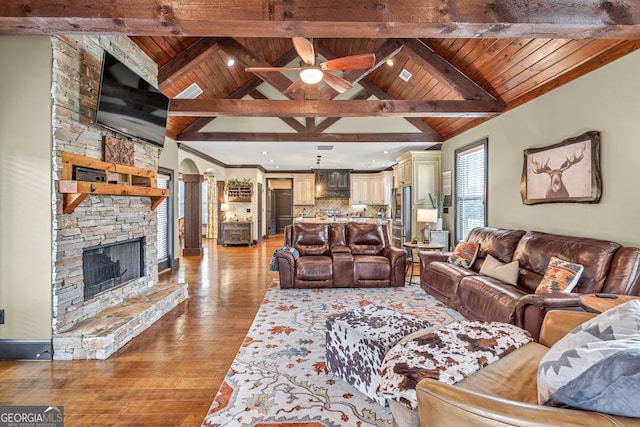 401 Sara Ct, Loganville, GA 30052 - living area featuring arched walkways, a stone fireplace, wooden ceiling, and light wood-style flooring