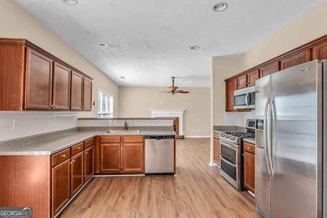 362 Interlake Pass, Mcdonough, GA 30252 - kitchen featuring stainless steel appliances, a sink, a peninsula, a ceiling fan, and light wood-type flooring