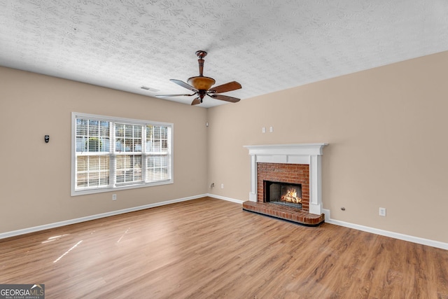 362 Interlake Pass, Mcdonough, GA 30252 - unfurnished living room featuring ceiling fan, wood finished floors, a brick fireplace, baseboards, and a textured ceiling