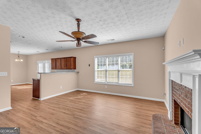 362 Interlake Pass, Mcdonough, GA 30252 - unfurnished living room featuring a brick fireplace, a ceiling fan, baseboards, a chandelier, and light wood-type flooring