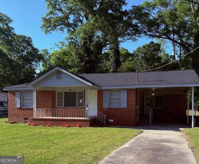 ranch-style home with driveway, brick siding, covered porch, and a front yard