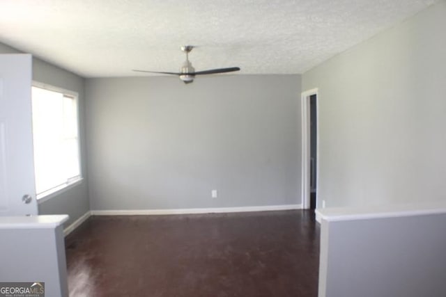 unfurnished room featuring a ceiling fan, baseboards, and a textured ceiling
