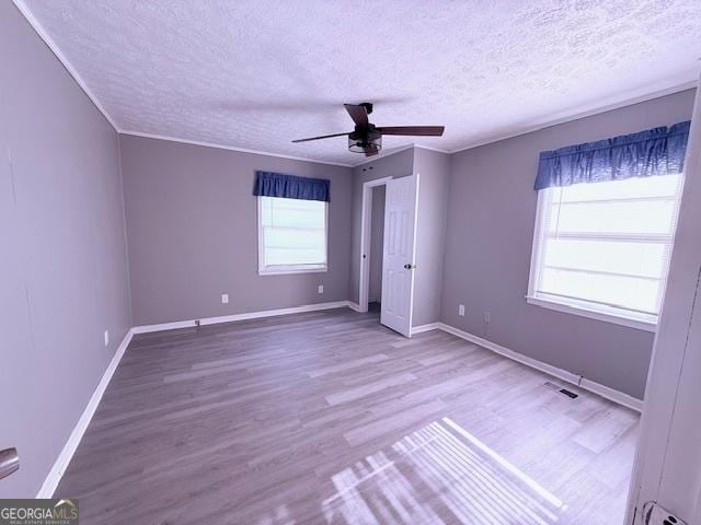 unfurnished bedroom featuring a textured ceiling, wood finished floors, baseboards, and a ceiling fan