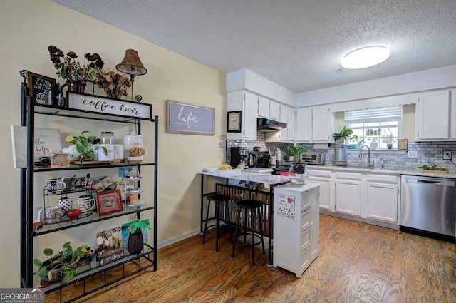 kitchen with white cabinets, a sink, a textured ceiling, dishwasher, and under cabinet range hood