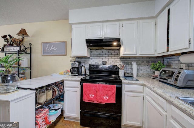 kitchen with white cabinets, a toaster, under cabinet range hood, black electric range, and tasteful backsplash