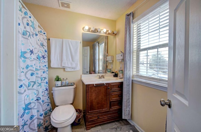 bathroom with a textured ceiling, vanity, baseboards, toilet, and visible vents