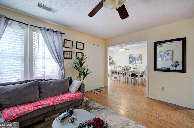 living area with visible vents, ceiling fan, and a healthy amount of sunlight