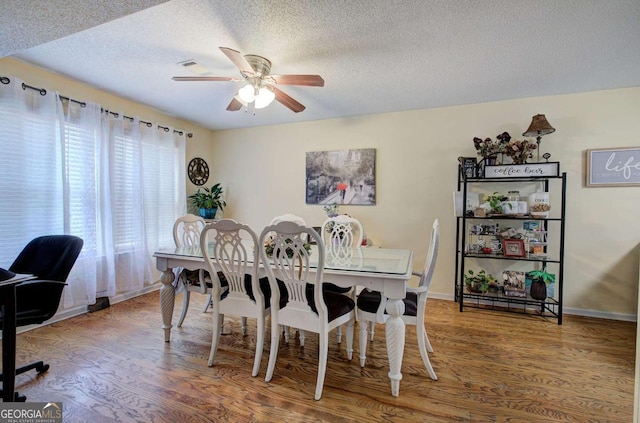 dining area with baseboards, wood finished floors, a textured ceiling, and ceiling fan