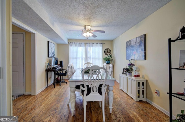 dining room featuring baseboards, wood finished floors, a textured ceiling, and ceiling fan