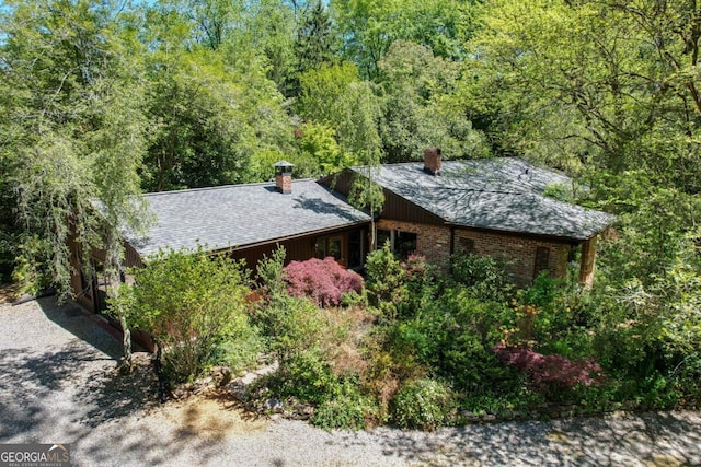 1144 Evergreen Dr NE, Atlanta, GA 30319 - view of side of home featuring a chimney, a wooded view, and a shingled roof